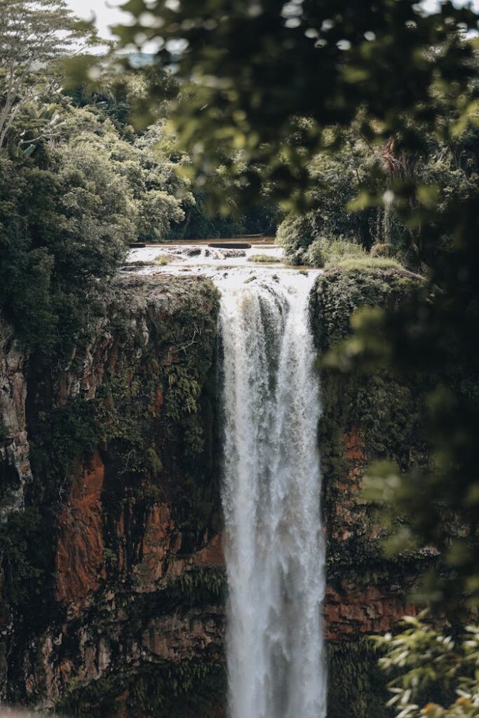 Stunning waterfall cascading down a cliff surrounded by dense green foliage in Mauritius.