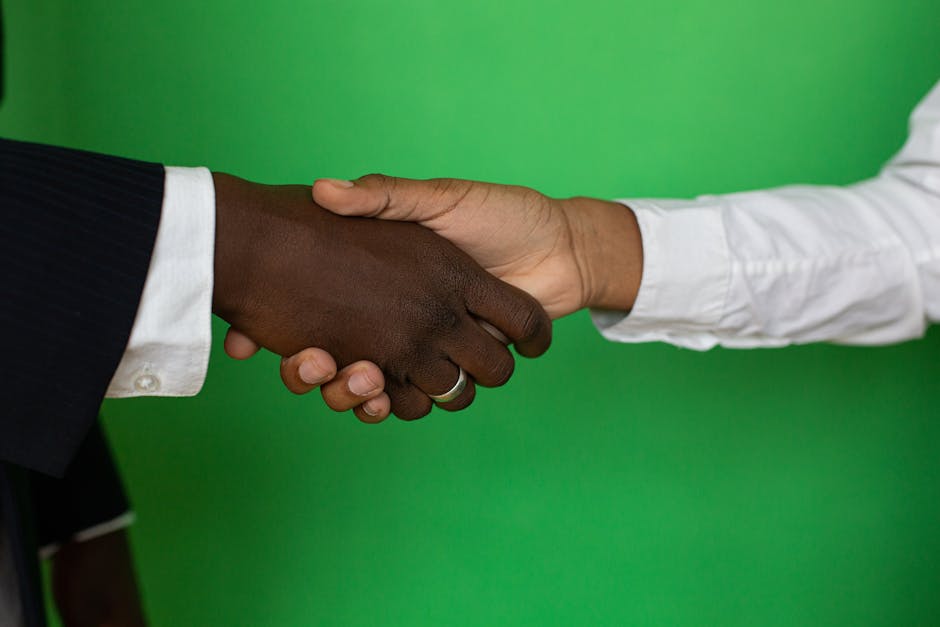 Two diverse hands shaking towards a successful business deal on a green background.